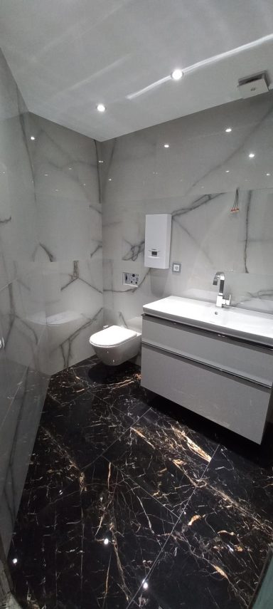 Modernes Badezimmer mit marmorierten Wänden, Waschbecken und WC.